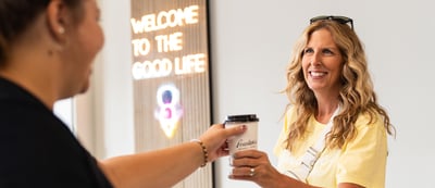 a woman is handing a cup of coffee to a customer