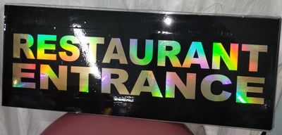 a restaurant entrance sign with a rainbow - colored sign