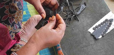 "Tribal artisan shaping wax mold to cast brass idol in traditional lost-wax method"