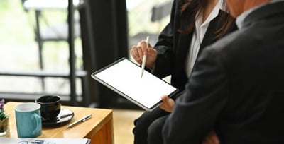 a man and woman sitting at a table with a tablet