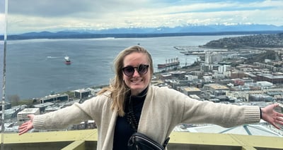 a woman on top of the space needle with the puget sound and olympics in the background