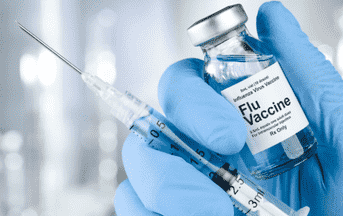 a person in gloves holding a flu vaccine and a syringe