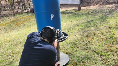 Man using Self-defense firearm (Carbine) kneeling from behind a barrier on training range.