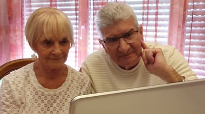 a man and woman sitting at a table with a laptop