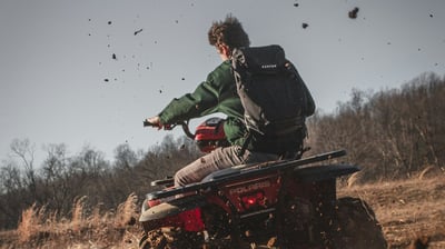 Tourist riding ATV through muddy jungle trails and rice fields in Bali on an off-road adventure tour