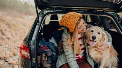 mujer sentada en coche con su perro