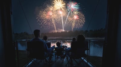 a family watching fireworks in the night sky on an RV deck