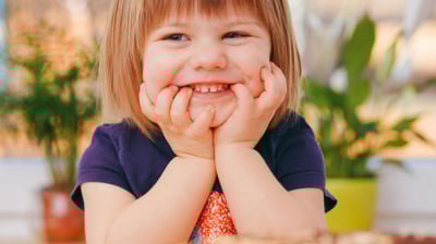a little girl smiling at the table with a cake