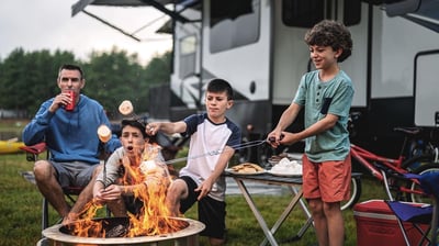 a group of people sitting around a fire pit roasting marshmellows