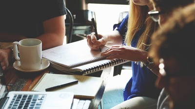 a woman sitting at a table with a notebook and a notebook