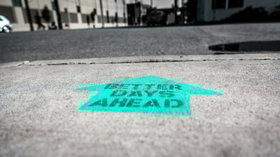 cyan arrow on concrete saying better days ahead