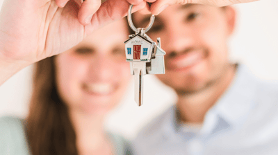a man and woman holding keys to their house