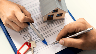 a person holding a pen and writing on a clipboard