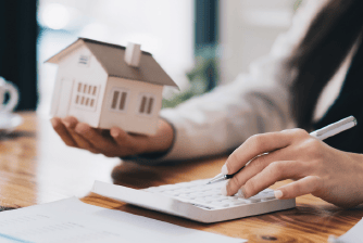 a woman is holding a house model and a pen