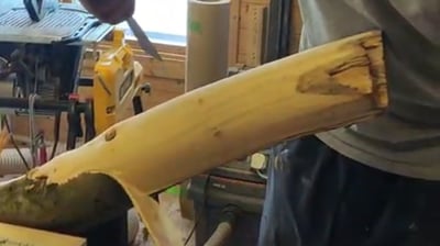 a man is stripping the bark off a log in a workshop 