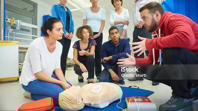 a group of people standing around a dummy in a hospital