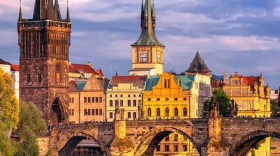 a bridge over a river with a clock tower in the background