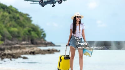 a woman standing on a beach with a suitcase and a suitcase