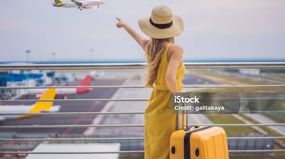 a woman in a yellow dress and hat, holding a suitcase