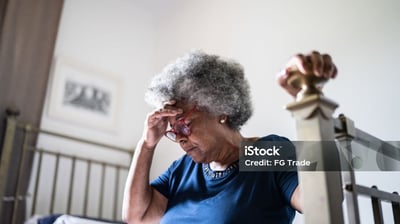 a woman in a blue shirt and glasses looking at her phone