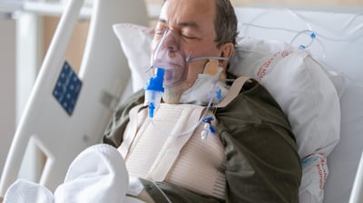 a man in a hospital bed with a mask on