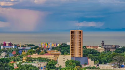 a helicopter flying over a city with a rainbow colored sky