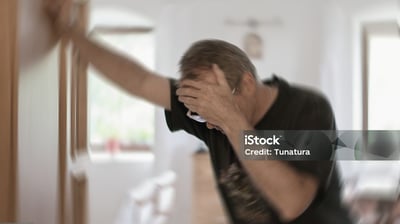 a man holding his hand up to his face while he is holding a remote control
