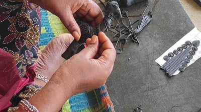 "Tribal artisan shaping wax mold to cast brass idol in traditional lost-wax method"