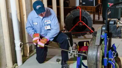 A man in a blue shirt is inserting a camera into a lateral for inspection from the cleanout