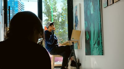 a man sitting on a chair in front of a painting