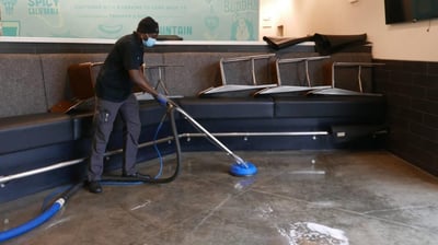 a man cleaning a couch with a vacuum