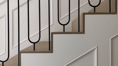 Custom staircase design with curved metal balusters and wood handrail for upscale interior