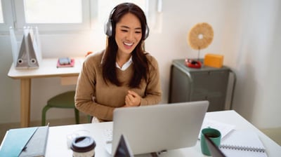 a woman with headphones at a laptop, engaged in an intensive language course with her tutor