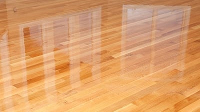 Newly finished hardwood floors shining under natural light, showcasing the rich texture & warm tones