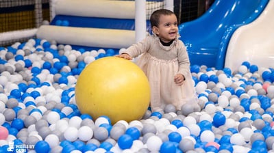 a baby girl in a ball pit with a ball in the middle of a ball