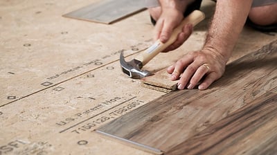 a man is using a hammer to install a laminate floor