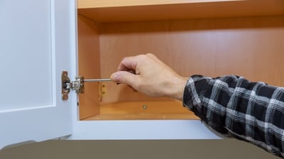 a person holding a screwdriver fixing a cabinet