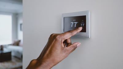 picture of someone adjusting a smart thermostat