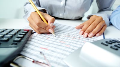 a person is holding a pencil and writing on a paper