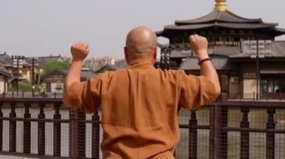 a man in a brown shirt and jeans standing on a bridge