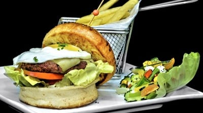un burger avec une salade en accompagnement