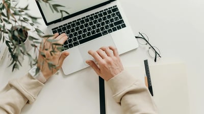 a person's hands typing on a laptop computer