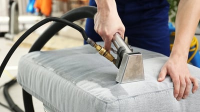 a person cleaning a couch with a vacuum