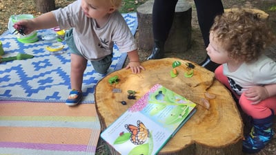 two young children playing with toys and a book