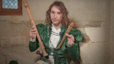a man in a green jacket holding two wooden sticks