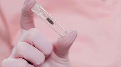 a person in a gloved hand holding an implant
