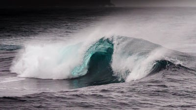 "Powerful ocean wave crashing in the Faroe Islands, with turquoise highlights and a dramatic dark se