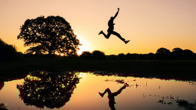 Mann springt vor Sonnenuntergang als Zeichen für das befreite Gefühl nach der Hypnose.