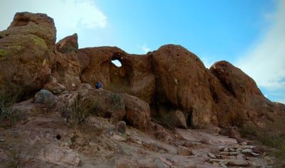 a desert rock formation with a hole showing blue sky behind