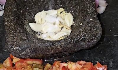 ail et sel dans un pilon avec des tomates coupées